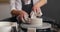 Front view of mother and son hands making ceramic pot on pottery wheel. Hands of adult and child making pottery, working