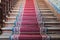 Front view of old ascending wooden stairs with ornate red carpet