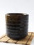 Front view of organic Cassia herb Tea in pottery cup on the bamboo coaster isolated on a white background.