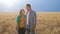 Front view of a pair of young farmers agronomists standing in the background of a wheat field.