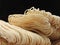 Front view of a pile of raw thin noodles  isolated on black background. Food ingredients. Asian, Taiwanese cuisine ingredients.