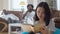 Front view portrait of absorbed intelligent beautiful Asian woman reading book with blurred African American men resting