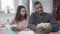 Front view portrait of African American rich man counting dollars sharing money with teen girl sitting at table in