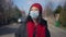 Front view portrait of young Asian woman in Covid face mask strolling outdoors on sunny spring autumn day. Relaxed