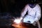 Front view of professional welder man welding steel with spark in the factory with copy space background. Industrial concept.