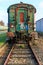 Front view of rusty and corroded green metal freight car on disused train tracks