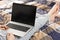 Front view on a screen of a laptop on the knees of a woman in a grey flowered nightwear. Home office concept. Freelancer works in