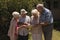 Front view of senior friends discussing over digital tablet in garden