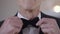 Front view senior male hands adjusting bow tie in slow motion close-up. Unrecognizable confident Caucasian groom