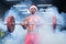 Front view of a sexy muscular man wearing Christmas hat and red shorts lifting a barbell in a gym standing in smoke