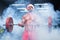 Front view of a sexy muscular man wearing Christmas hat and red shorts lifting a barbell in a gym standing in smoke