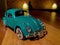 Front view shot of a  diorama Turquoise Volkswagen Beetle toy car in a garage