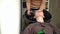 Front view slim young Caucasian woman sitting in hair salon with head in sink and unrecognizable hairdresser washing