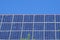 Front view of solar panels on a roof with deep blue cloudless sky in background. Photovoltaic installation of a house in daylight