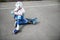 Front view of a sporty boy in safety helmet sitting on skateboard and putting on protective knee pads