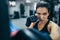 Front view of strong brunette attractive female trainer punching a bag with kickboxing gloves in the gym workout. Sport, fitness,