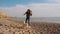 Front view of teenager girl playing with stick with her active white shiba inu puppy on the beach slow motion