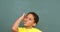 Front view of thoughtful African American schoolboy standing against chalkboard in classroom 4k