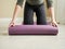 Front view to woman which rolls out a yoga mat. Girl at home preparing to training. Healthy active lifestyle concept