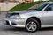 Front view Toyota Caldina car of 2000 release in the back of a silver T210 station wagon in a parking lot with a green lawn