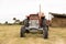 Front view of a tractor standing in a crop field. The day is cloudy. Concept of agriculture