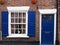 front view of a typical old small english terraced brick house with blue painted door and shutters