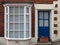 front view of a typical old small english terraced brick house with blue painted door white bay windows