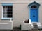 front view of a typical old small english terraced brick house white painted wall and blue door
