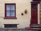 front view of a typical old small english terraced brick house with yellow painted walls and maroon window and doors