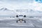 Front view of the white business jet taxiing on airport taxiway in winter on the background of high scenic snow capped mountains