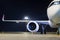 Front view of a white passenger airplane connected to an external power supply on an airport night apron