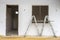 Front view of window and door frame, ladder and white concrete wall in incomplete house building site