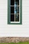 Front view of a window in a white painted clapboard church building trimmed in green