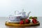 Front view of a wooden tray on a table with three strawberries next to a cup of tea, seletive focus  white background