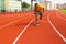 Front view of young afro american male sprinter in yellow sportswear running on the sport track. Concentrated tired