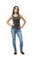 Front view of young beautiful woman in gray sleeveless top and blue jeans standing looking at camera with hands on hips