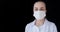 A front view of a young intellectual doctor in a medical mask on a black background with text space