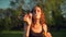 Front view of Young pretty adult girl making soap bubbles. Beautiful tree with orange leaves.