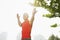 Front view of young, smiling, muscular man in a red shirt stretching by a tree, arms outstretched in Beijing, China