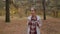 Front view of young woman with backpack walking in autumn park - steadicam shot