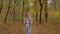 Front view of young woman with backpack walking in autumn park - steadicam shot