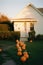 Front yard facade of a suburb house with a lot of halloween pumpkins. Soft evening light, autumn vibes. Y2K aesthetics