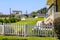 The front yard of the yellow lighthouse with a white picket fence. lush green grass and flowers with blue sky at Point Fermin Park