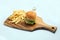 Frontal Hero Shot of a grilled chicken slider burger, fries on a wooden platter board, on a minimal white background with a