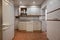 Frontal image of kitchen furnished with white furniture with wooden details