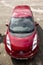 The frontal part of red Nissan Leaf electric car after rain in sunny weather