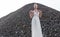 Frontal portrait of blonde woman with hair tight up in white bride dress, in day time, over piles of stones. Copy space