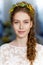 Frontal portrait of a young beautiful woman with long hair and grey eyes with a tiara of natural mimosa twig