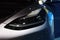 Frontal view advanced xenon head-lights of Tesla car model Y in liquid silver, Mercury Silver Metallic color, popular passenger