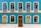 Frontal view of a house facade covered in azulejo tiles with broken windows and wooden door